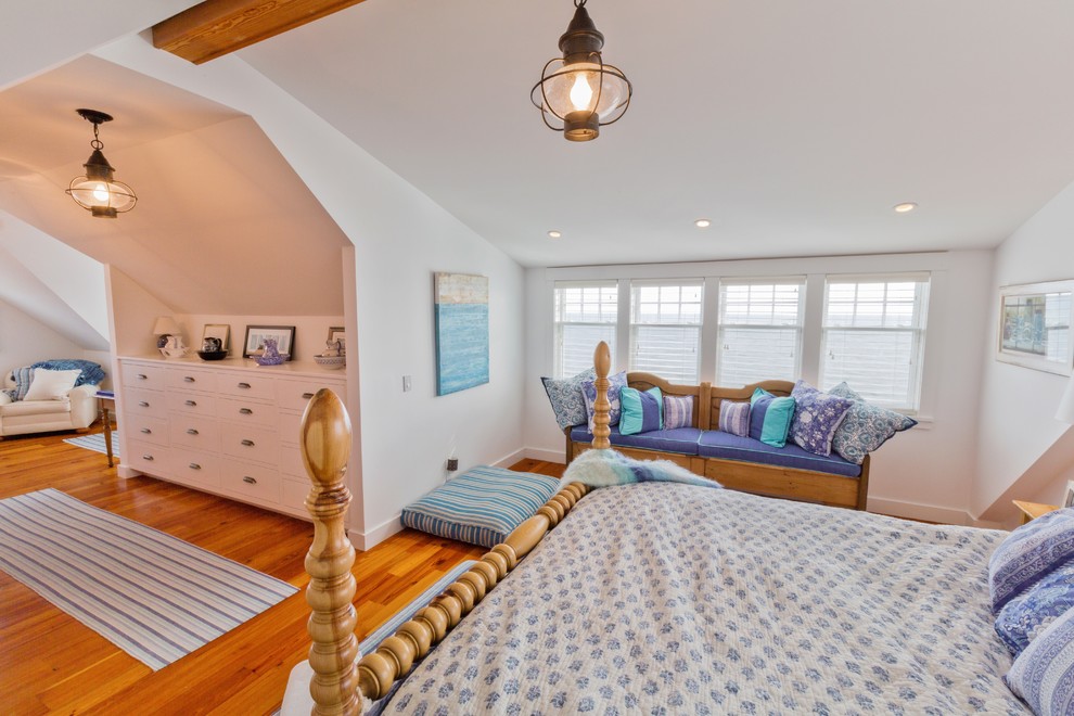 This is an example of a beach style master bedroom in Boston with white walls and medium hardwood floors.