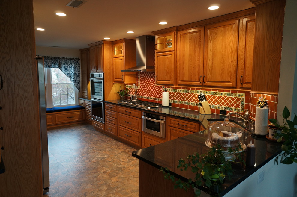 This is an example of a small l-shaped eat-in kitchen in Philadelphia with an undermount sink, raised-panel cabinets, medium wood cabinets, quartz benchtops, brown splashback, terra-cotta splashback, stainless steel appliances, linoleum floors and no island.
