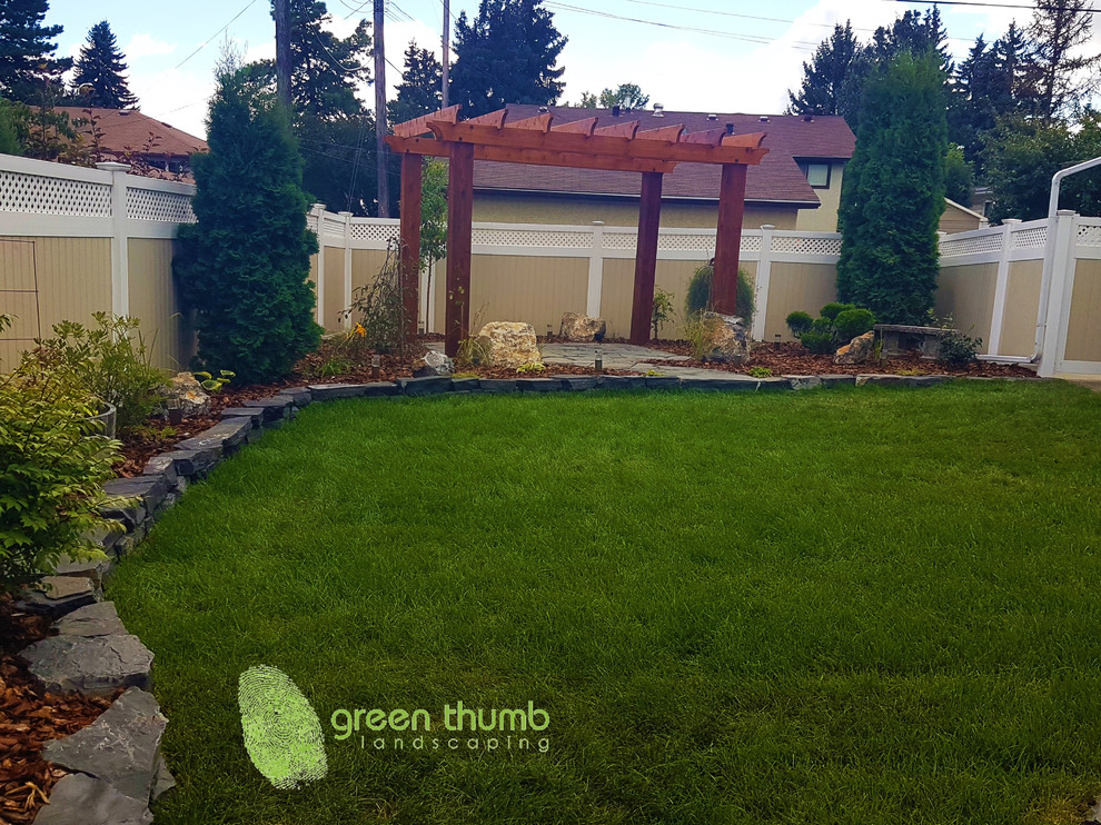 Design ideas for a rustic full sun backyard stone retaining wall landscape in Edmonton for summer.