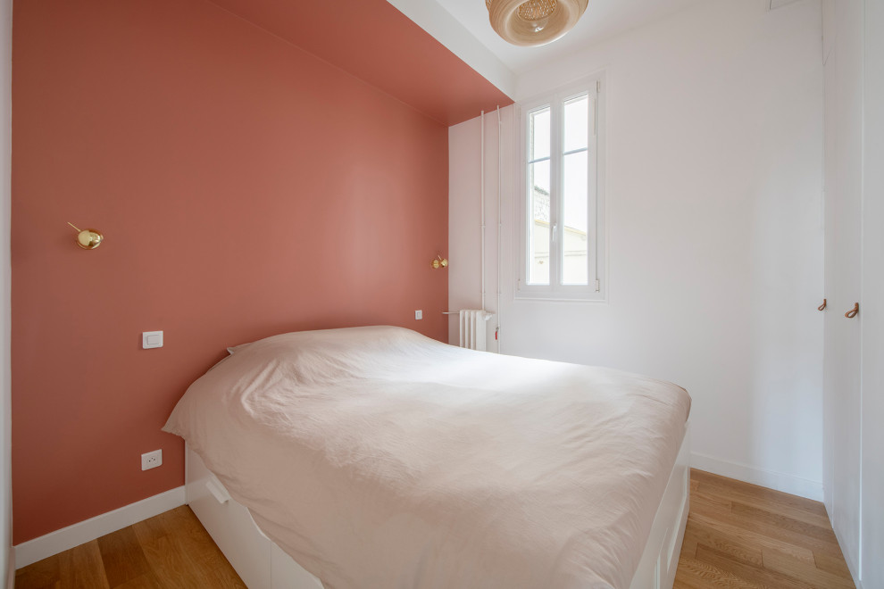 Foto de dormitorio principal de tamaño medio sin chimenea con paredes rojas, suelo de madera clara y suelo beige