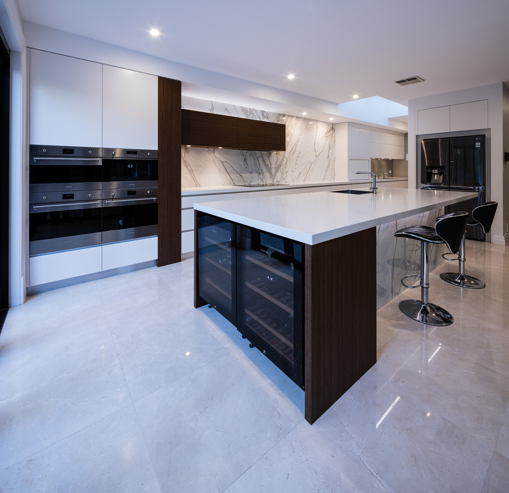This is an example of an expansive contemporary single-wall kitchen in Sydney with an undermount sink, flat-panel cabinets, white cabinets, marble benchtops, glass sheet splashback, stainless steel appliances, porcelain floors, with island, multi-coloured floor and multi-coloured benchtop.