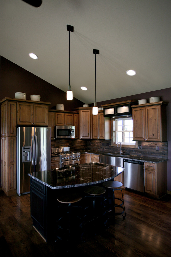 Example of a mid-sized mountain style l-shaped dark wood floor and brown floor open concept kitchen design in Minneapolis with a farmhouse sink, raised-panel cabinets, medium tone wood cabinets, granite countertops, brown backsplash, wood backsplash, stainless steel appliances and an island