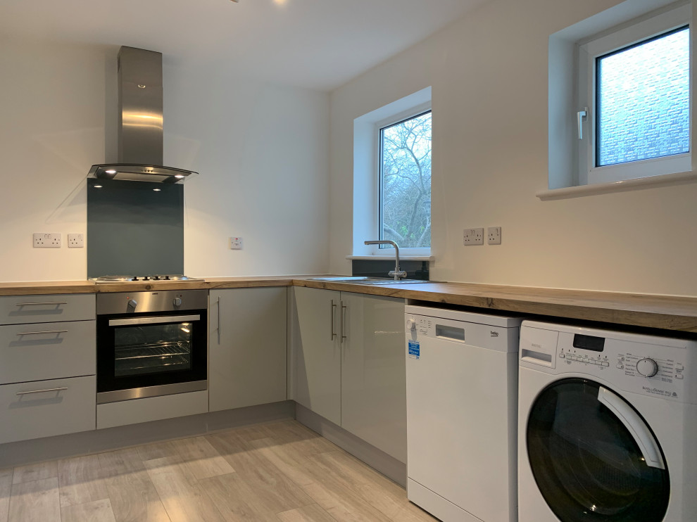 Inspiration for a small modern galley enclosed kitchen in Buckinghamshire with a single-bowl sink, flat-panel cabinets, turquoise cabinets, wood worktops, green splashback, metal splashback, white appliances, laminate floors, no island, multi-coloured floors and multicoloured worktops.