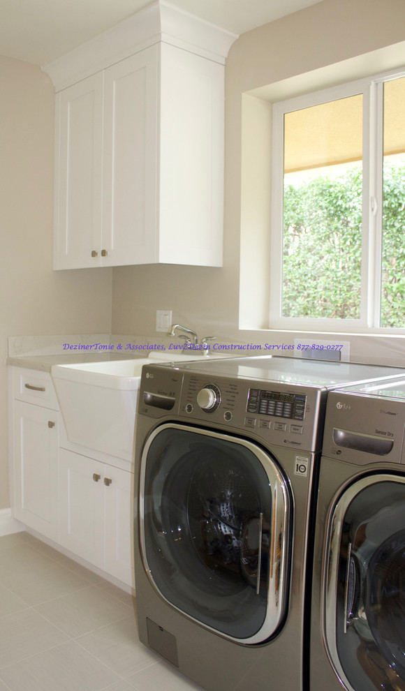 Photo of a mid-sized modern galley dedicated laundry room in Miami with a farmhouse sink, recessed-panel cabinets, white cabinets, quartz benchtops, beige walls, porcelain floors and a side-by-side washer and dryer.