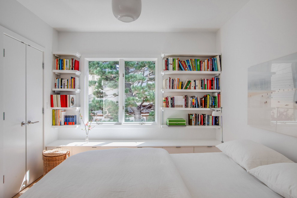 Diseño de habitación de invitados minimalista con paredes blancas y suelo de madera clara