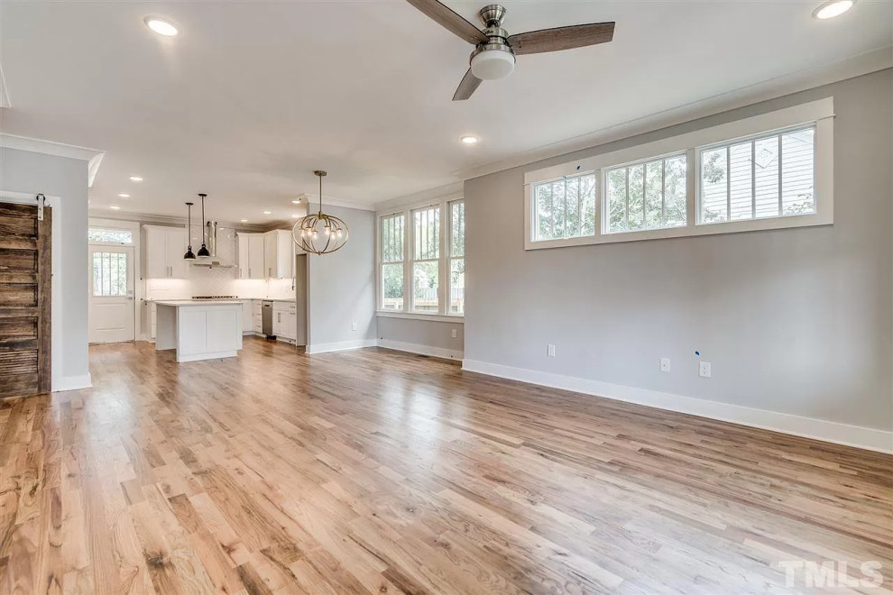 This is an example of a mid-sized arts and crafts open concept family room in Raleigh with light hardwood floors.