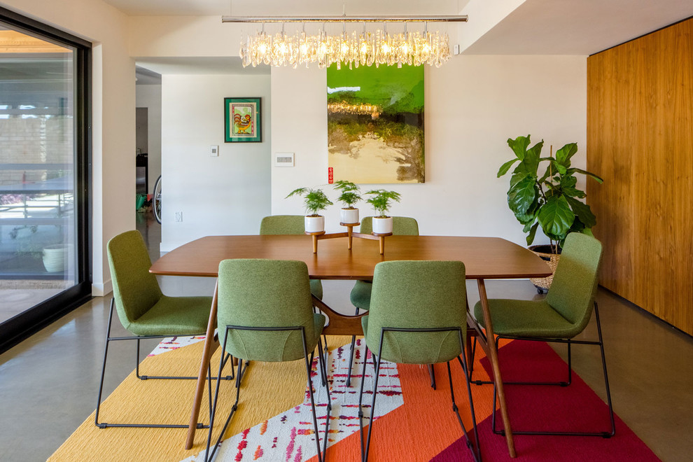 This is an example of a midcentury dining room in Phoenix with white walls, concrete floors and grey floor.