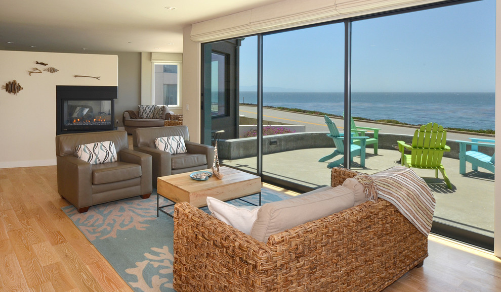Beach style open concept living room in San Francisco with beige walls, light hardwood floors, a two-sided fireplace and a metal fireplace surround.