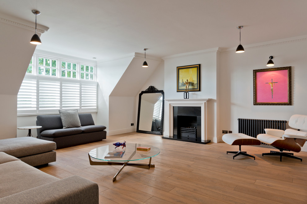 This is an example of a contemporary formal living room in London with white walls, medium hardwood floors, a standard fireplace and no tv.