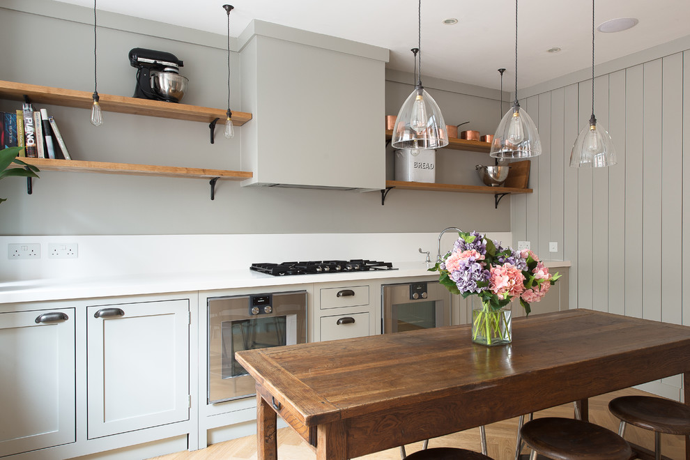 Photo of a small transitional kitchen in London with shaker cabinets, light wood cabinets and medium hardwood floors.