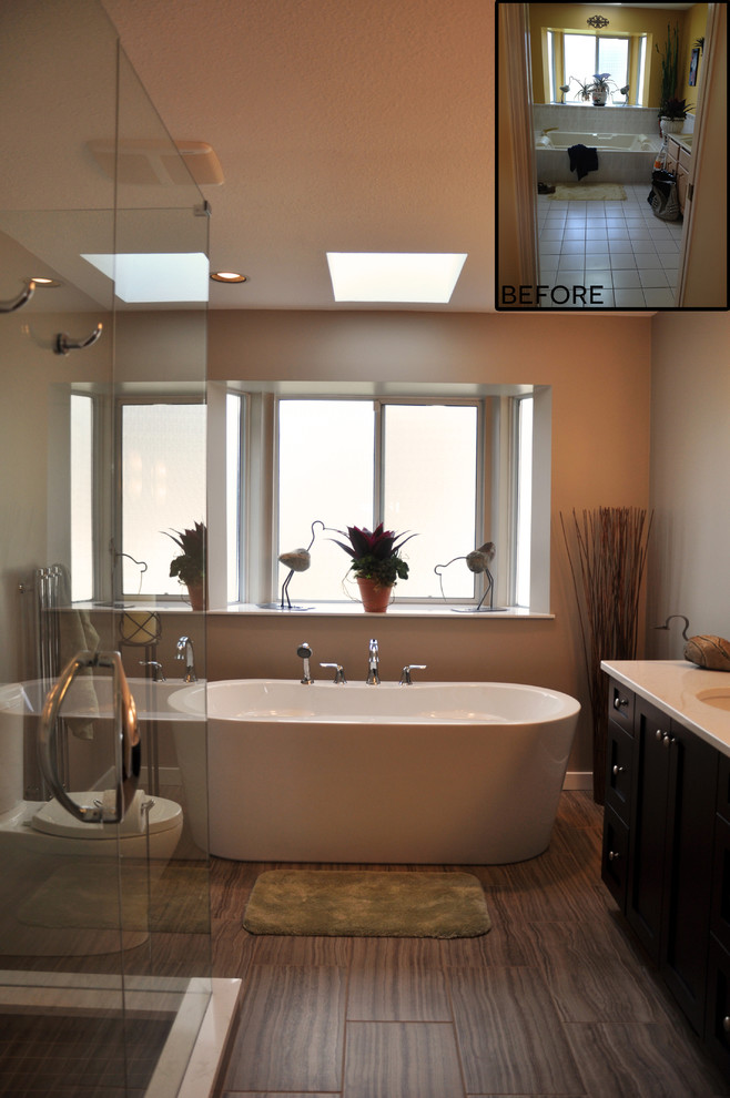 This is an example of a mid-sized transitional master bathroom in Vancouver with shaker cabinets, brown cabinets, a freestanding tub, a corner shower, a two-piece toilet, gray tile, ceramic tile, grey walls, ceramic floors, an undermount sink and engineered quartz benchtops.
