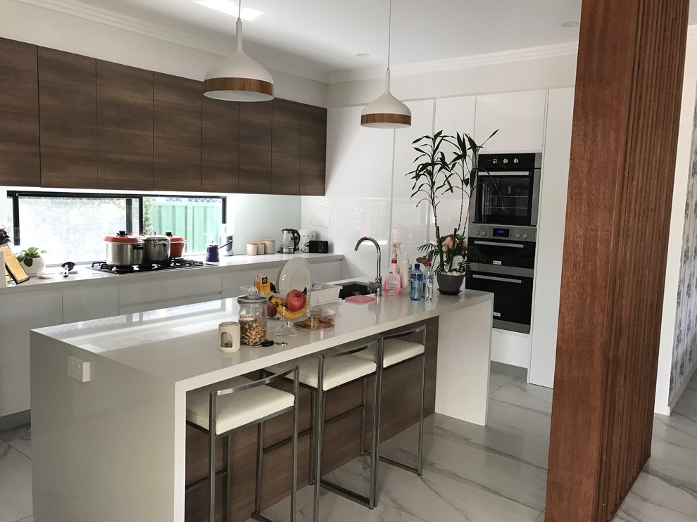 This is an example of a mid-sized contemporary galley kitchen pantry in Sydney with flat-panel cabinets, brown cabinets, granite benchtops, white splashback, marble floors, multiple islands, white floor, a drop-in sink, window splashback and stainless steel appliances.