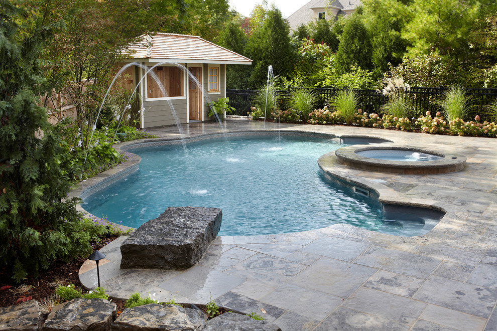 Photo of a mid-sized traditional backyard custom-shaped pool in Toronto with a water feature and natural stone pavers.