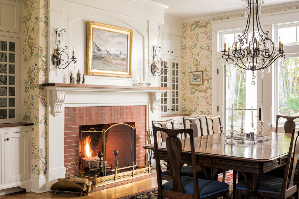 This is an example of a mid-sized traditional dining room in Portland Maine with multi-coloured walls, a standard fireplace, a brick fireplace surround, medium hardwood floors and brown floor.