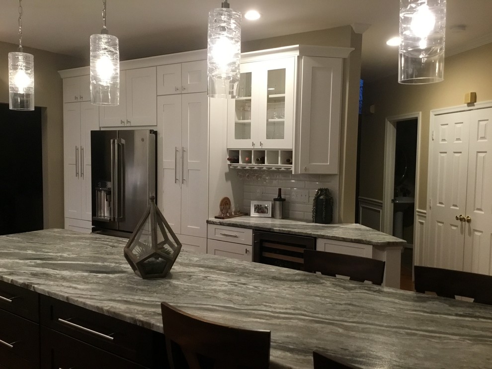 Example of a mid-sized transitional u-shaped medium tone wood floor and brown floor open concept kitchen design in DC Metro with an undermount sink, white cabinets, granite countertops, white backsplash, subway tile backsplash, stainless steel appliances, an island, gray countertops and shaker cabinets