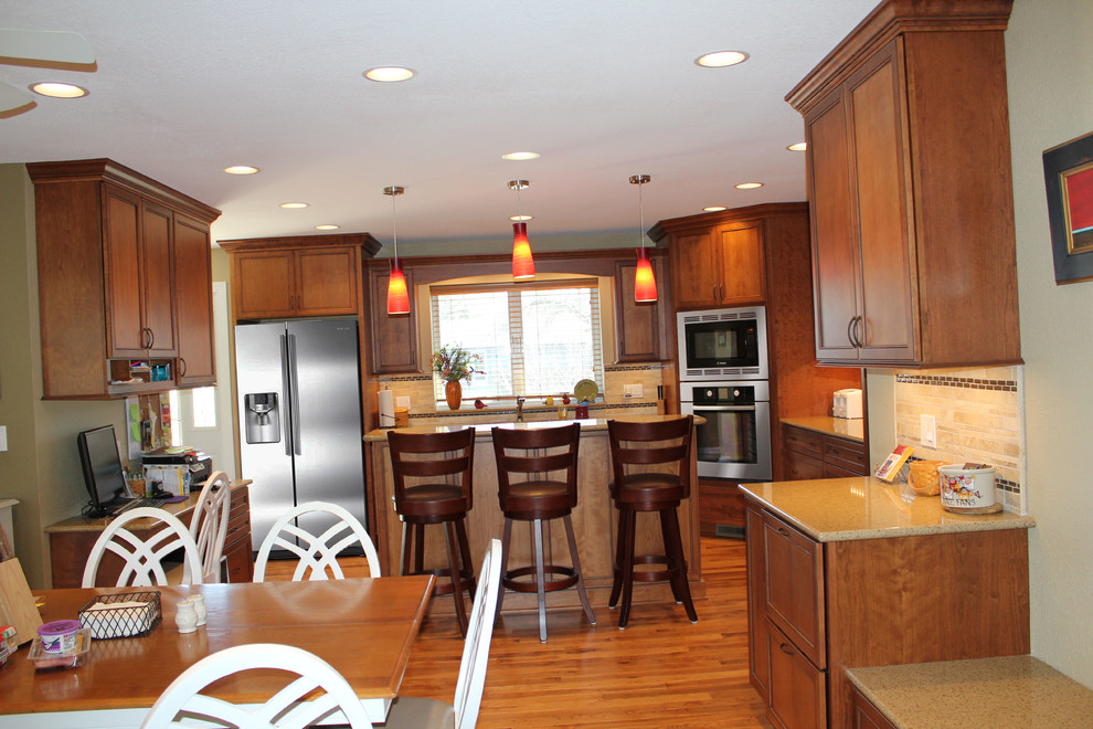 Large transitional l-shaped medium tone wood floor eat-in kitchen photo with an undermount sink, recessed-panel cabinets, medium tone wood cabinets, quartz countertops, stone tile backsplash, stainless steel appliances, green walls and an island