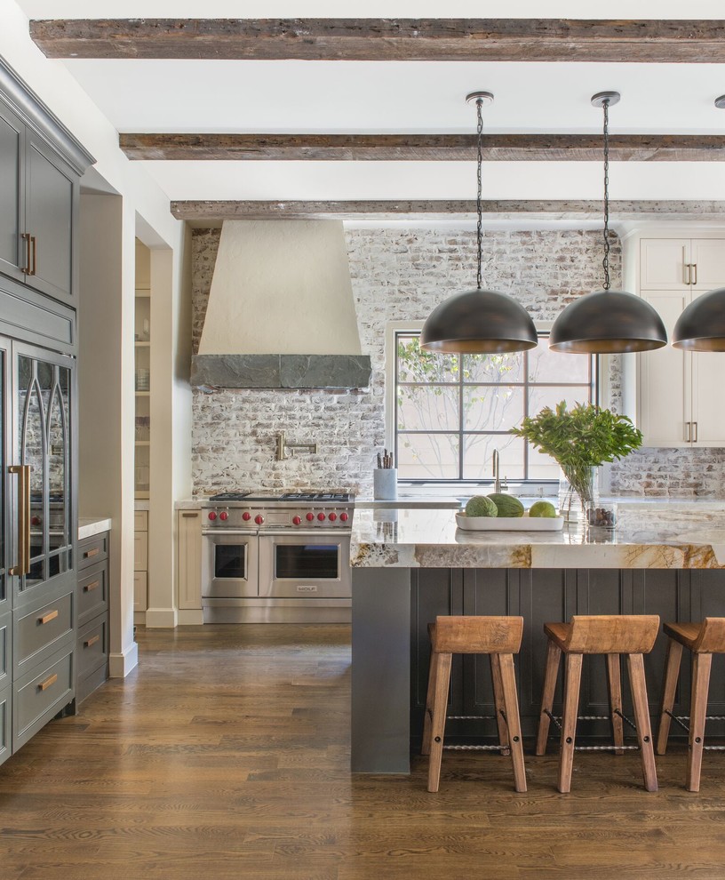 Design ideas for a country l-shaped kitchen in Dallas with grey cabinets, brick splashback, stainless steel appliances, medium hardwood floors, with island, brown floor, beige benchtop and recessed-panel cabinets.