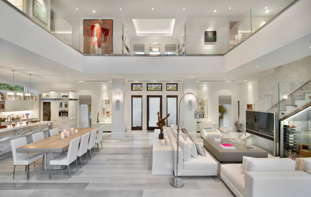 Contemporary open concept living room in Miami with white walls, light hardwood floors, a freestanding tv and grey floor.