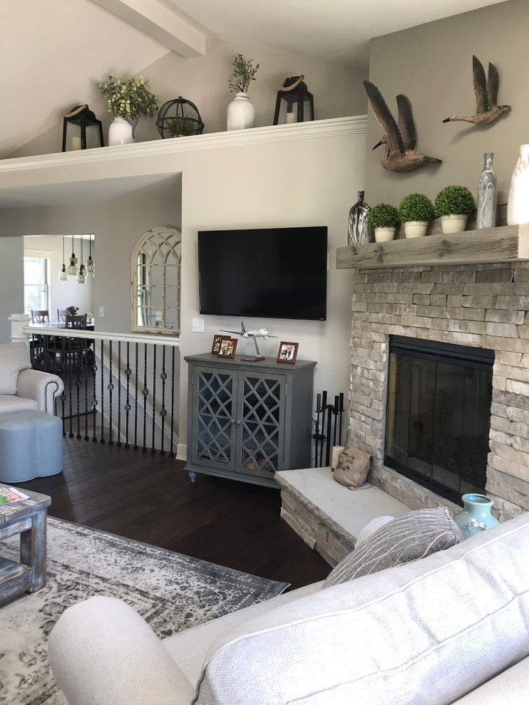 Inspiration for a mid-sized arts and crafts open concept family room in St Louis with grey walls, dark hardwood floors, a corner fireplace, a stone fireplace surround, a wall-mounted tv and brown floor.