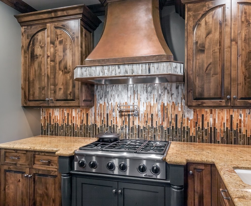 Huge transitional u-shaped dark wood floor open concept kitchen photo in Omaha with a farmhouse sink, medium tone wood cabinets, granite countertops, multicolored backsplash, glass tile backsplash, stainless steel appliances and an island