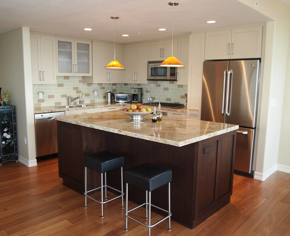 This is an example of a mid-sized transitional l-shaped eat-in kitchen in San Diego with an undermount sink, shaker cabinets, white cabinets, granite benchtops, multi-coloured splashback, subway tile splashback, stainless steel appliances, medium hardwood floors and with island.