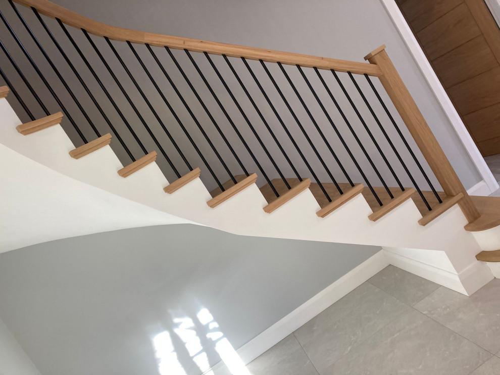 Источник вдохновения для домашнего уюта: изогнутая бетонная лестница в стиле модернизм с деревянными ступенями и деревянными перилами
