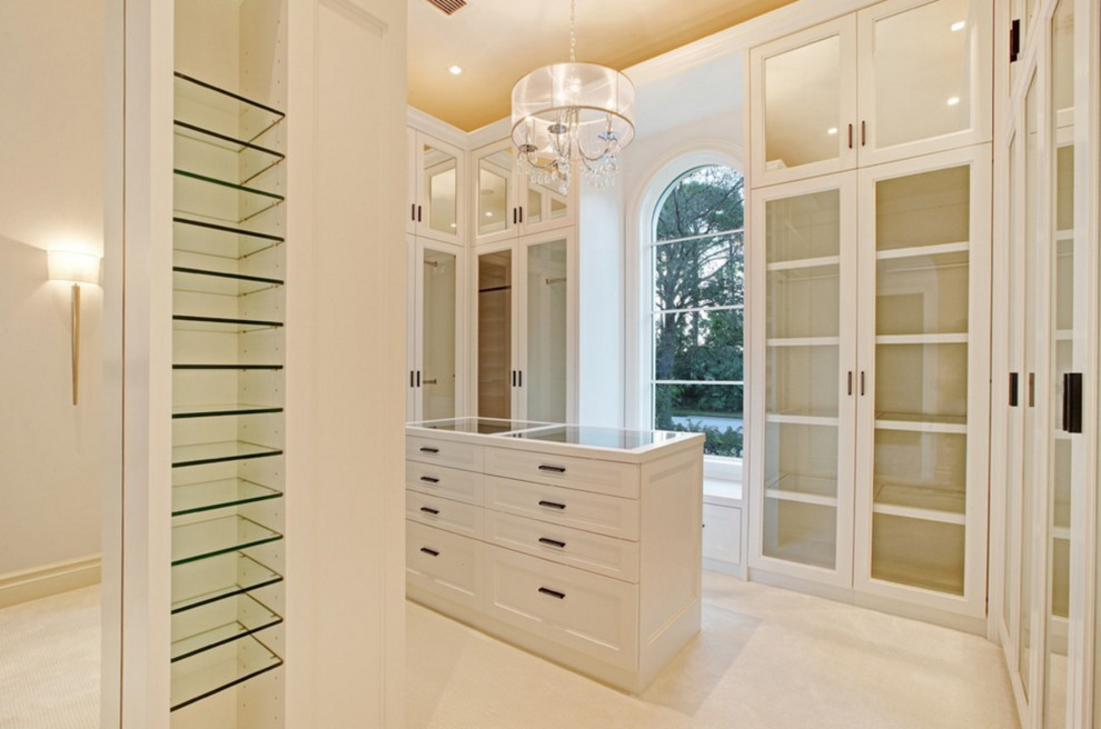 Photo of a large mediterranean women's walk-in wardrobe in Miami with dark wood cabinets, carpet and glass-front cabinets.