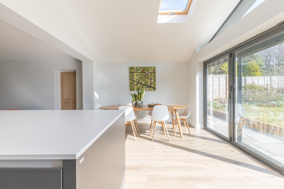 Design ideas for a mid-sized contemporary galley open plan kitchen in Sussex with an integrated sink, flat-panel cabinets, grey cabinets, solid surface benchtops, stainless steel appliances, with island and white benchtop.