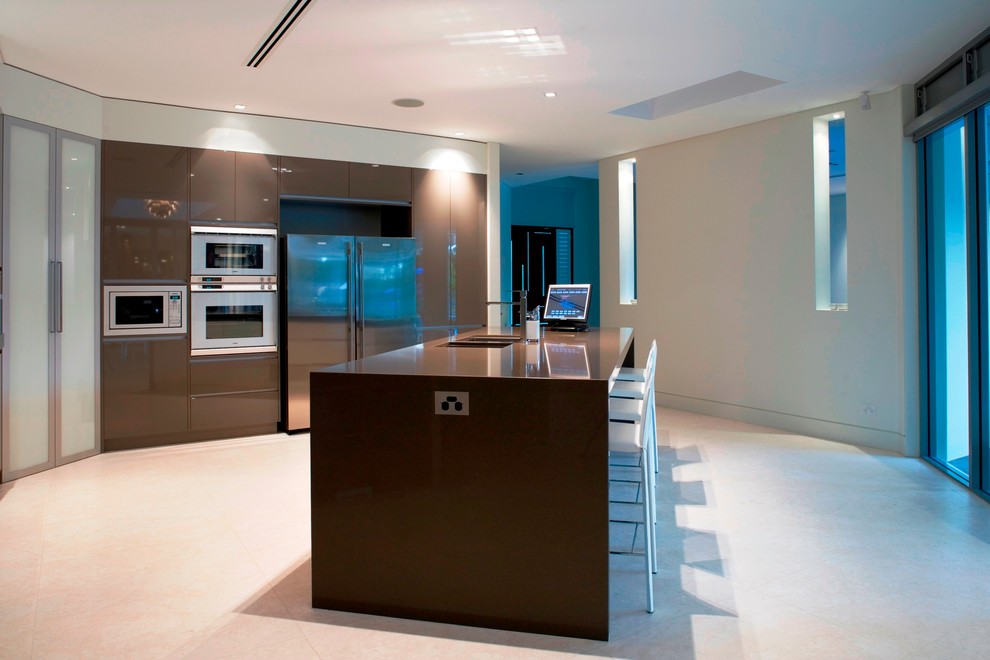 Photo of a modern galley eat-in kitchen in Sydney with an undermount sink, glass-front cabinets, stainless steel cabinets, quartzite benchtops, stainless steel appliances, travertine floors and with island.