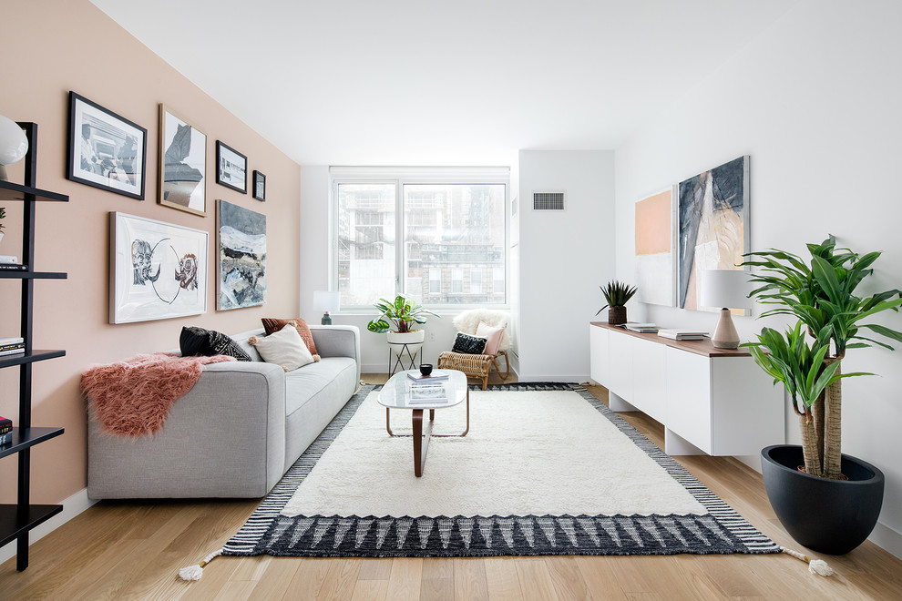 Design ideas for a scandinavian living room in New York with pink walls, light hardwood floors and beige floor.