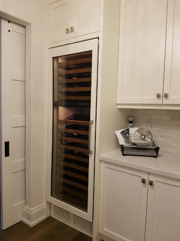 Inspiration for a mid-sized transitional l-shaped medium tone wood floor and brown floor open concept kitchen remodel in Toronto with an undermount sink, beaded inset cabinets, white cabinets, solid surface countertops, white backsplash, brick backsplash, stainless steel appliances, an island and white countertops