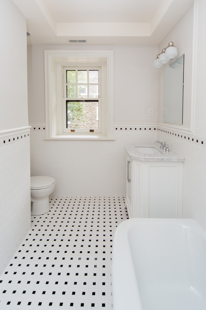 Photo of a mid-sized traditional bathroom in Philadelphia with white cabinets, white tile, white walls, an undermount sink, multi-coloured floor and recessed-panel cabinets.