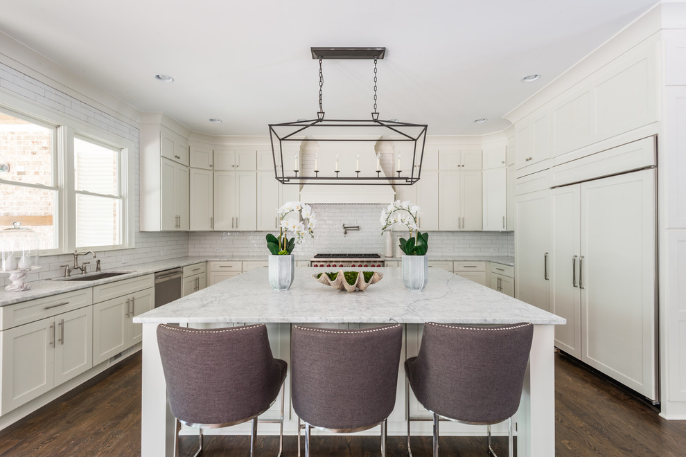 Traditional u-shaped kitchen in Atlanta with an undermount sink, shaker cabinets, white cabinets, white splashback, subway tile splashback, panelled appliances, dark hardwood floors, with island, brown floor and marble benchtops.