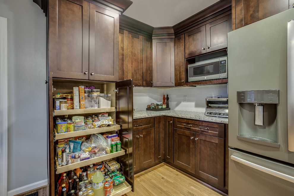 Inspiration for a mid-sized transitional l-shaped light wood floor and yellow floor eat-in kitchen remodel in Birmingham with a double-bowl sink, shaker cabinets, dark wood cabinets, granite countertops, white backsplash, subway tile backsplash, stainless steel appliances, an island and gray countertops