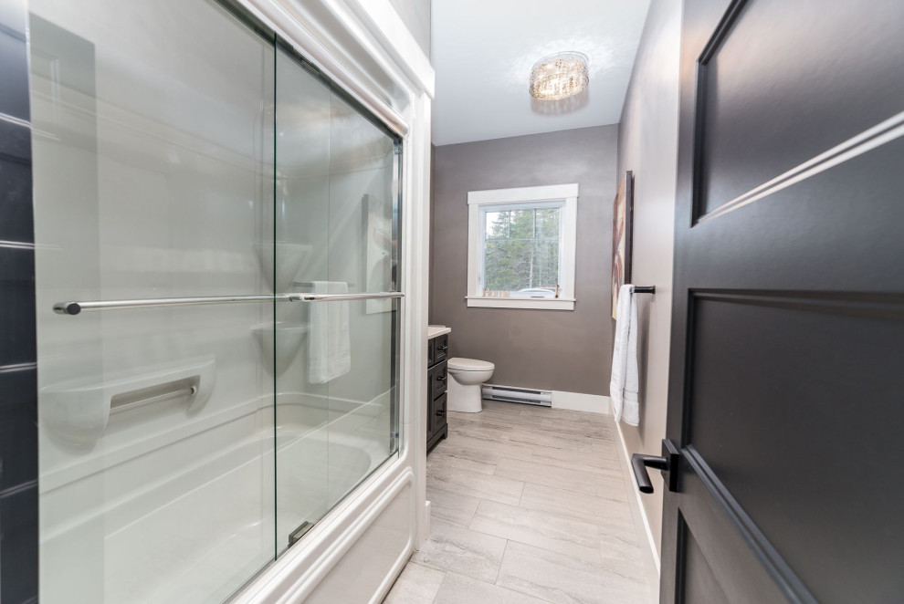 Tub/shower combo - large transitional ceramic tile and gray floor tub/shower combo idea with black cabinets, a two-piece toilet, beige walls and gray countertops