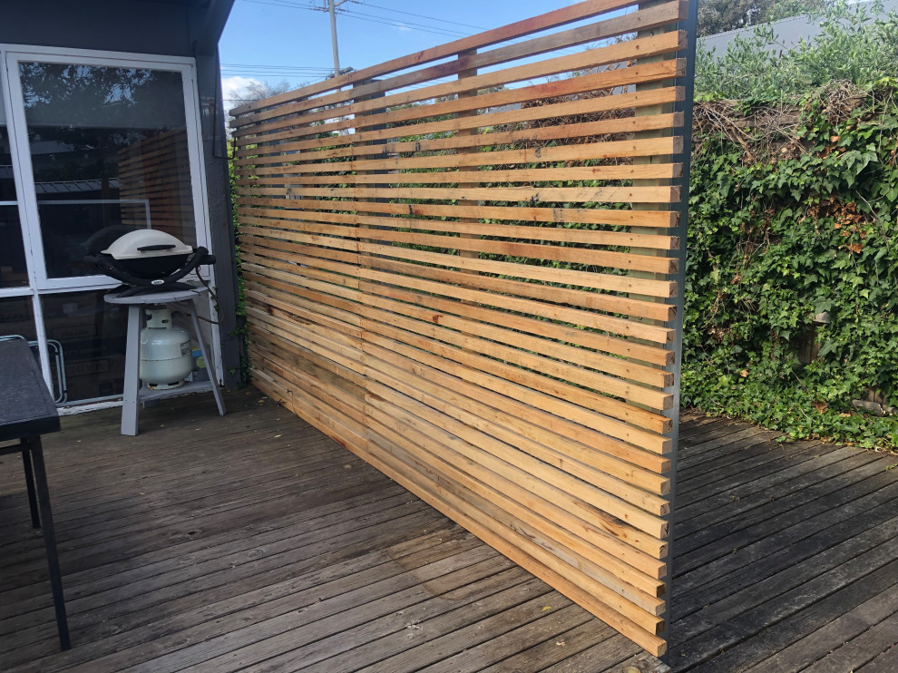 This is an example of a small contemporary backyard and ground level deck in Melbourne with with privacy feature, no cover and wood railing.