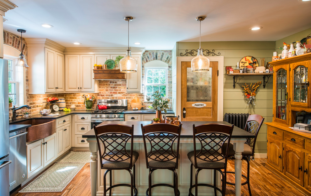 This is an example of a mid-sized country l-shaped eat-in kitchen in New York with a farmhouse sink, raised-panel cabinets, beige cabinets, granite benchtops, brown splashback, brick splashback, stainless steel appliances, dark hardwood floors, with island and brown floor.