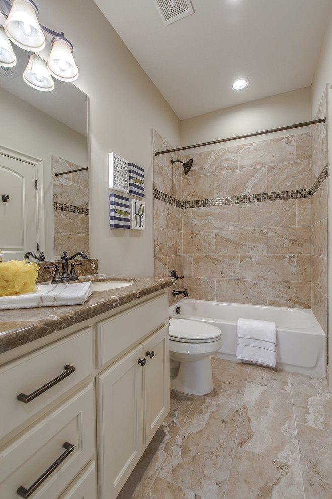 Design ideas for a mid-sized mediterranean kids bathroom in Houston with recessed-panel cabinets, white cabinets, an alcove tub, an alcove shower, a one-piece toilet, beige tile, ceramic tile, beige walls, cement tiles, an undermount sink, granite benchtops, beige floor and a shower curtain.