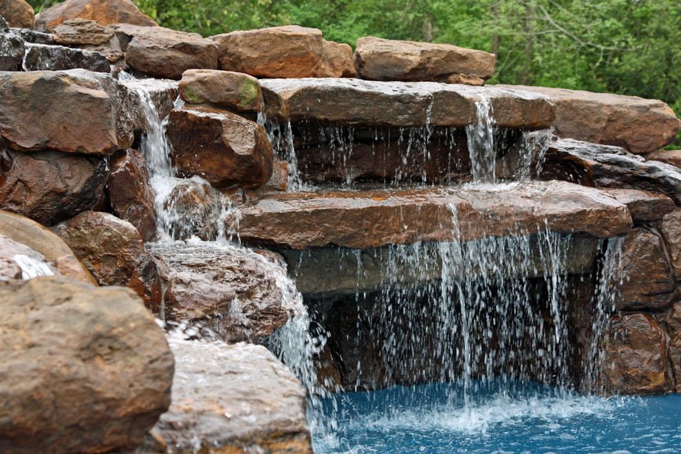 Large traditional backyard custom-shaped natural pool in Houston with a water slide and natural stone pavers.