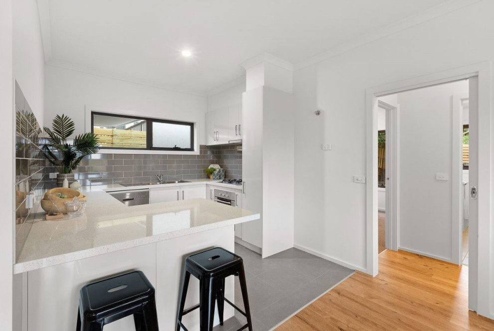 Design ideas for a small modern u-shaped separate kitchen in Melbourne with an integrated sink, flat-panel cabinets, white cabinets, quartz benchtops, grey splashback, ceramic splashback, stainless steel appliances, ceramic floors, no island, grey floor and white benchtop.