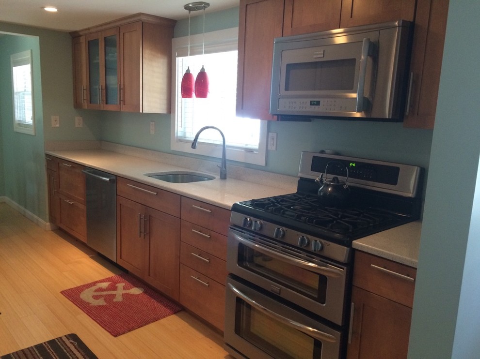 Example of a transitional galley light wood floor eat-in kitchen design in Boston with an undermount sink, shaker cabinets, medium tone wood cabinets, quartz countertops, stainless steel appliances, no island and white countertops