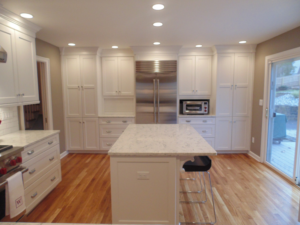 Eat-in kitchen - large transitional u-shaped medium tone wood floor and brown floor eat-in kitchen idea with an undermount sink, recessed-panel cabinets, white cabinets, quartz countertops, white backsplash, subway tile backsplash, stainless steel appliances, an island and white countertops