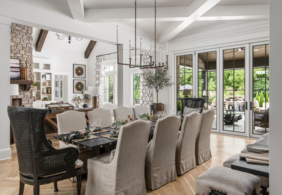 This is an example of a mid-sized transitional open plan dining in Nashville with white walls, medium hardwood floors, a standard fireplace, a stone fireplace surround and brown floor.