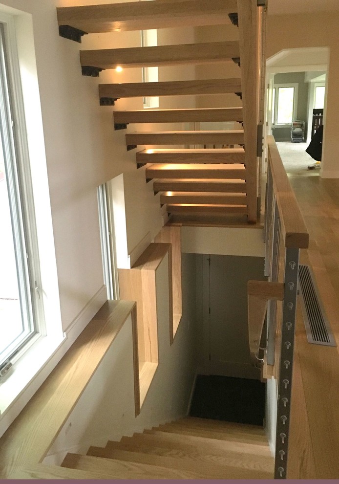 This is an example of a mid-sized contemporary wood straight staircase in Boston with open risers and cable railing.