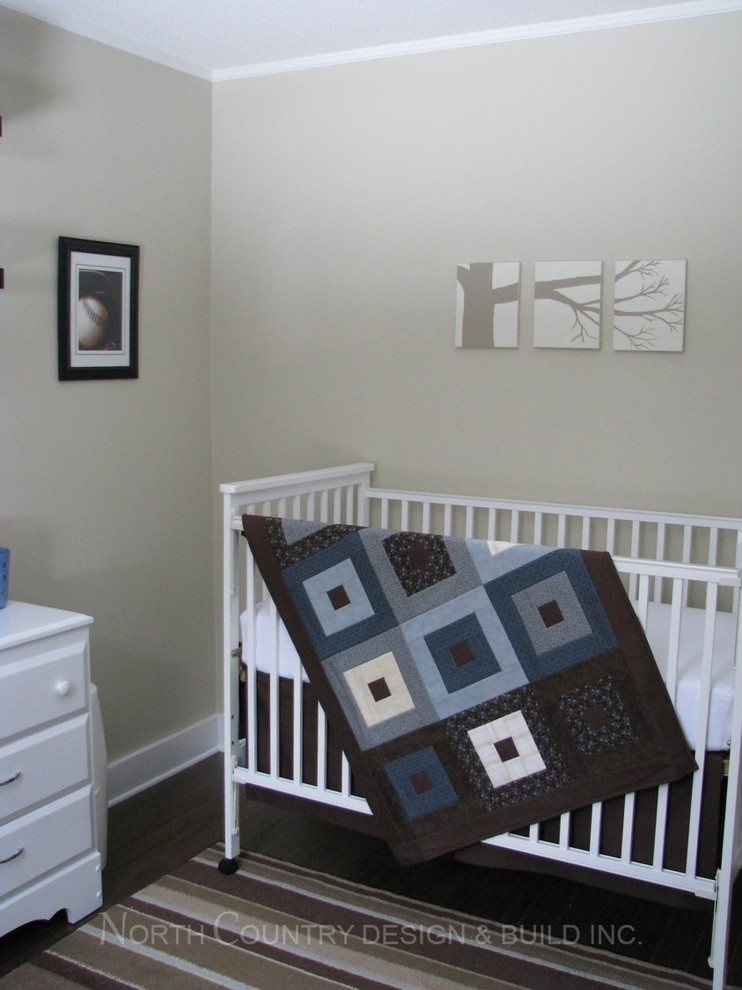 Small transitional nursery in Toronto with beige walls and dark hardwood floors for boys.