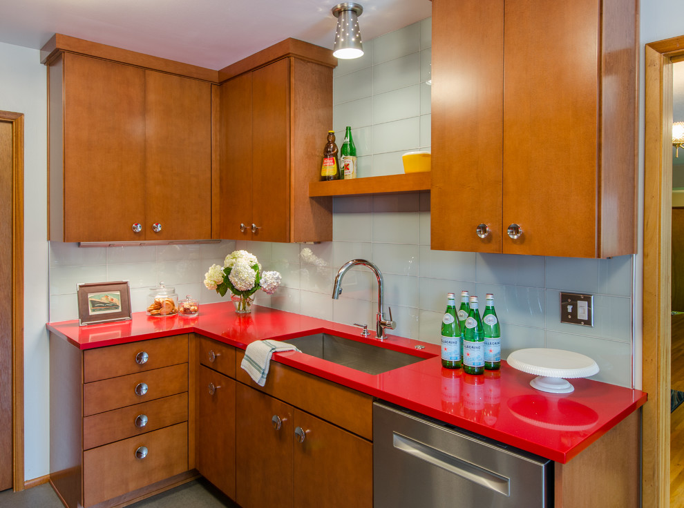 This is an example of a mid-sized midcentury galley separate kitchen in Seattle with a single-bowl sink, flat-panel cabinets, medium wood cabinets, quartz benchtops, glass tile splashback, stainless steel appliances, vinyl floors, no island and white splashback.