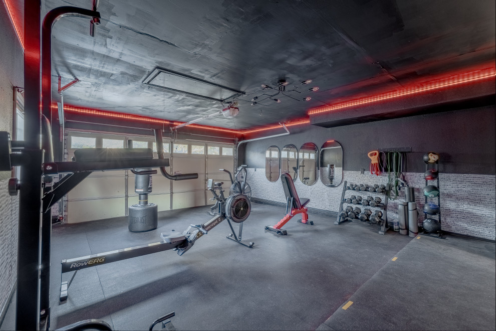 This is an example of a medium sized multi-use home gym in Austin with black walls and black floors.