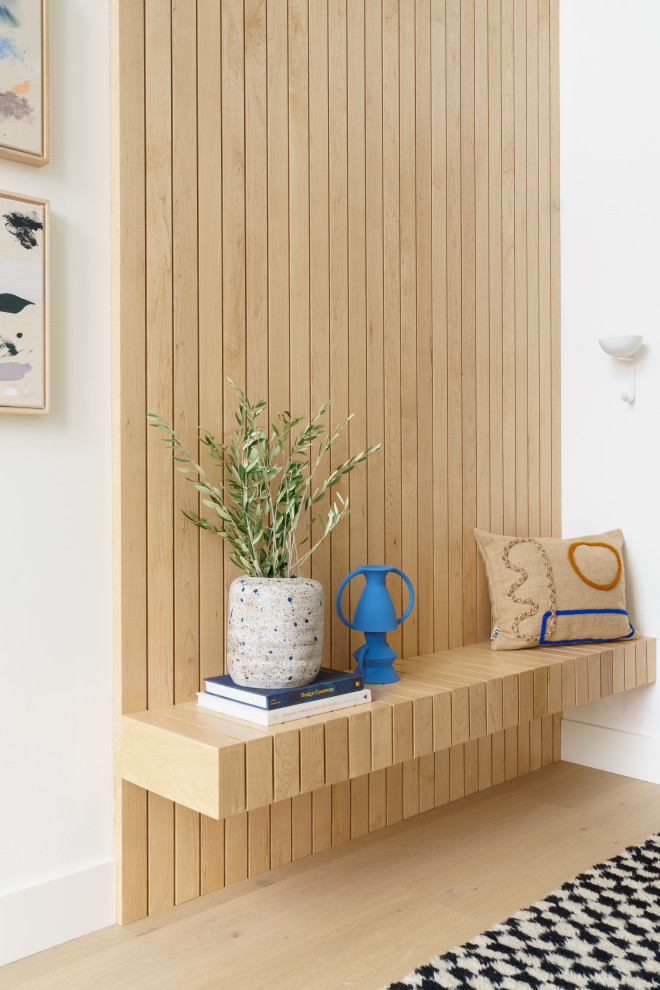 This is an example of a large beach style foyer in San Diego with white walls, light hardwood flooring, a pivot front door, a black front door, beige floors, a vaulted ceiling and wood walls.