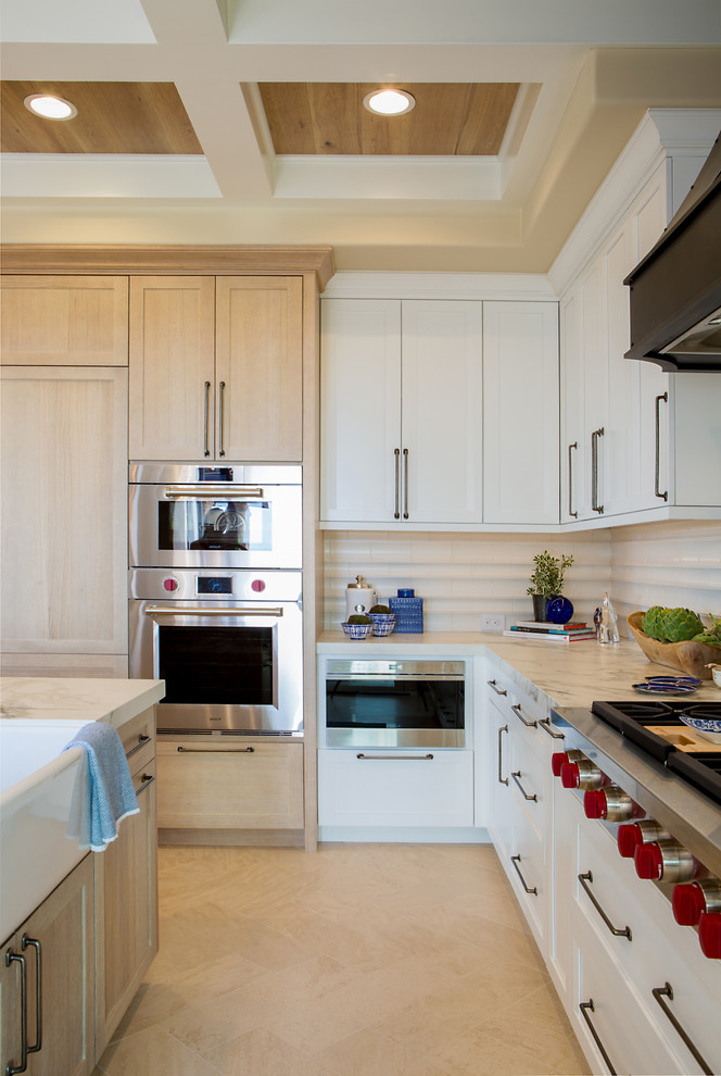 Inspiration for a large transitional l-shaped open plan kitchen in Denver with a farmhouse sink, recessed-panel cabinets, white cabinets, quartz benchtops, white splashback, ceramic splashback, panelled appliances, limestone floors, with island, beige floor and white benchtop.