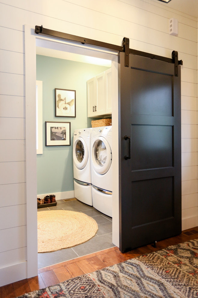 Inspiration for a mid-sized transitional single-wall utility room in Other with open cabinets, white cabinets, wood benchtops, blue walls, porcelain floors, a side-by-side washer and dryer, grey floor and brown benchtop.